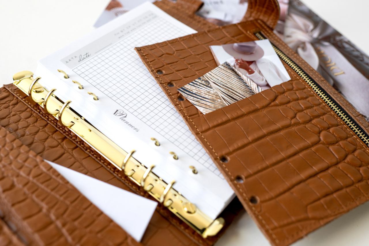 Close-up of rare brown leather A5 notebook cover with binder rings and documents inside.